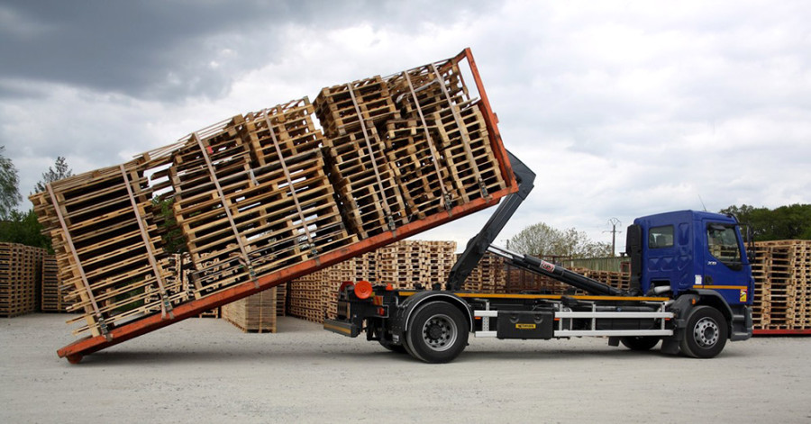 Notre camion dépose au sol un plateau de palettes usagées récupérées chez un client